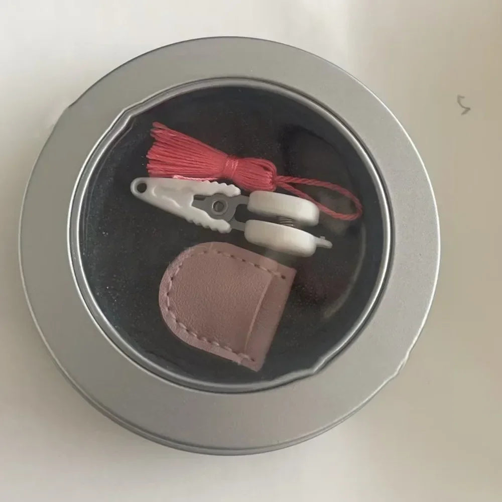 Mini precision sewing scissors with a protective cover and red thread inside a silver container.