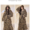 A woman models a long, patterned leopard print flannel kimono robe indoors.