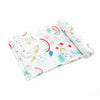 A rolled white muslin swaddle blanket featuring colorful unicorn and rainbow designs.