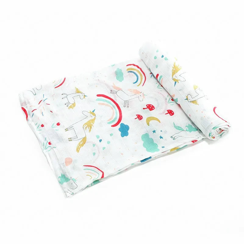 A rolled white muslin swaddle blanket featuring colorful unicorn and rainbow designs.