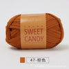 A ball of orange-brown hand-dyed fabric strip yarn labeled SWEET CANDY for crochet and knitting.