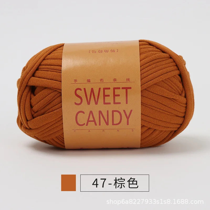 A ball of orange-brown hand-dyed fabric strip yarn labeled SWEET CANDY for crochet and knitting.
