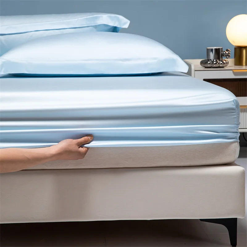 A hand touches a light blue bamboo bedding set on a bed.