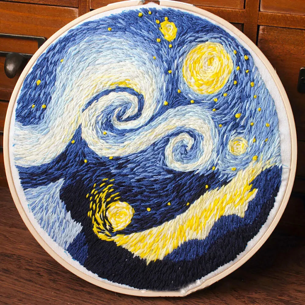 A cross stitch embroidery depicting a swirling night sky with yellow and blue stars and crescent moon.