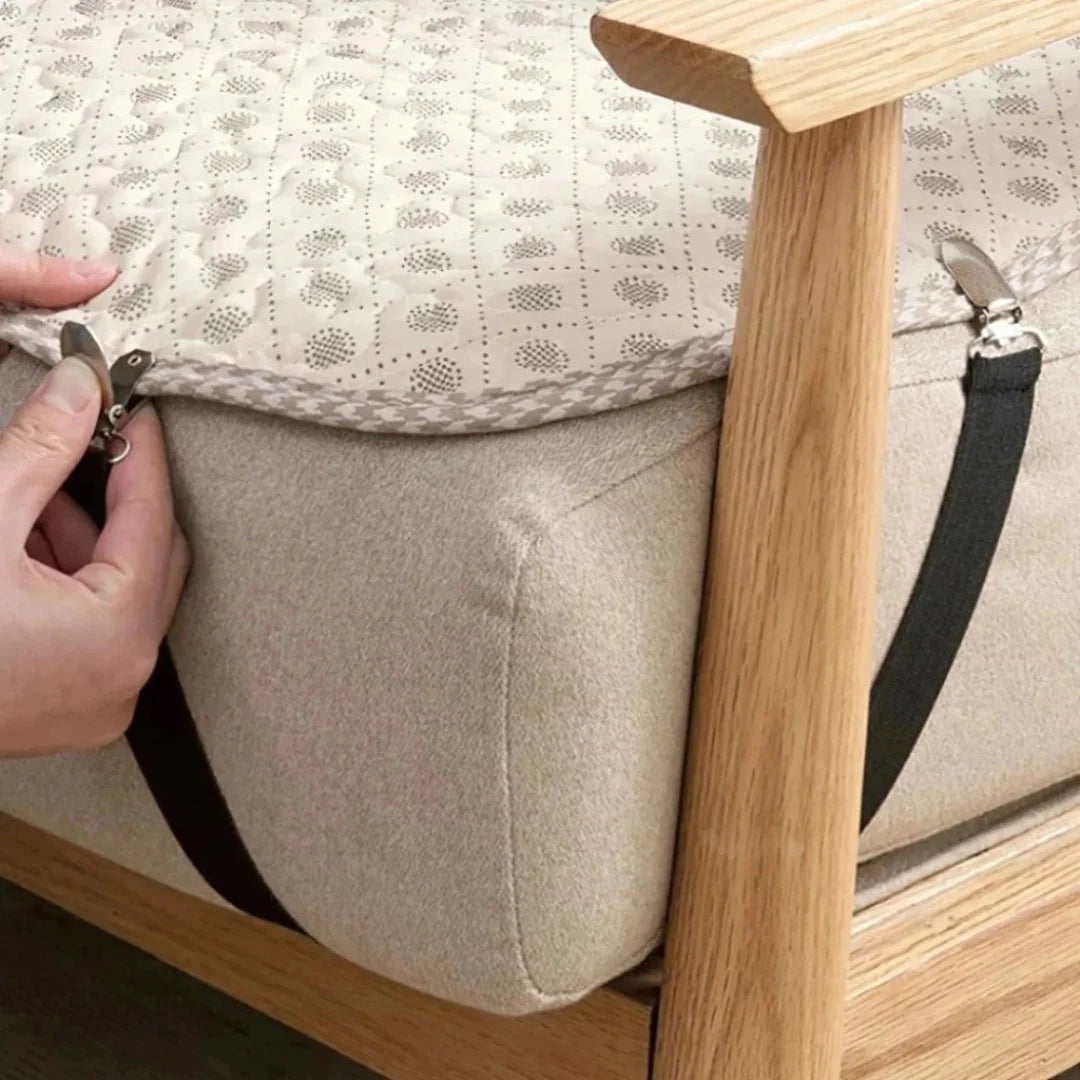 A hand is shown clipping a beige bed sheet to a light wood frame using black clips.