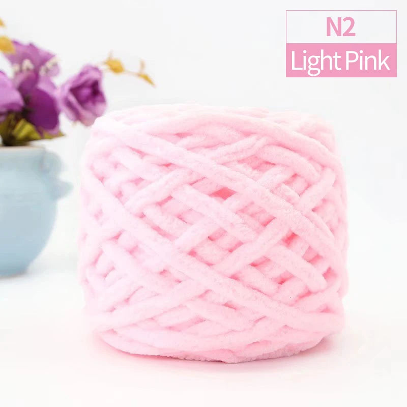 Light pink chunky velvet knitting yarn in a ball with purple flowers in the background