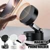A hand holds a smartphone above a magnetic phone holder with a vacuum suction base, demonstrating the foldable magnetic phone