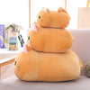 Three soft orange cat plush pillows stacked on a light surface.