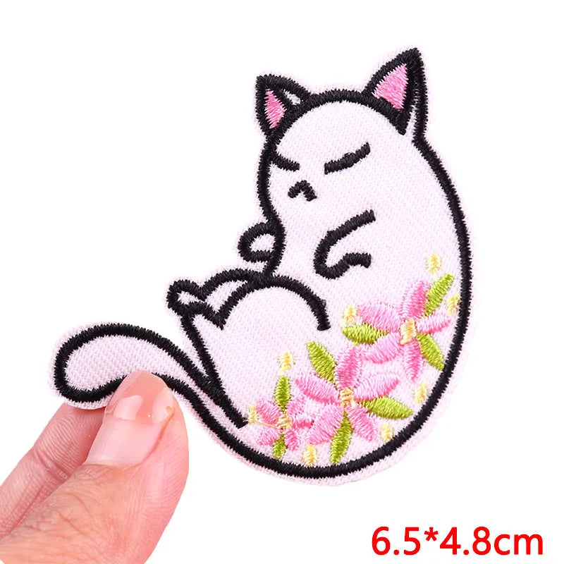 Pink and black embroidered patch of a sleeping cat with pink floral accents
