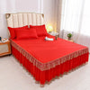 A bright red luxury floral bed skirt with lace trim covers a bed featuring a padded headboard.