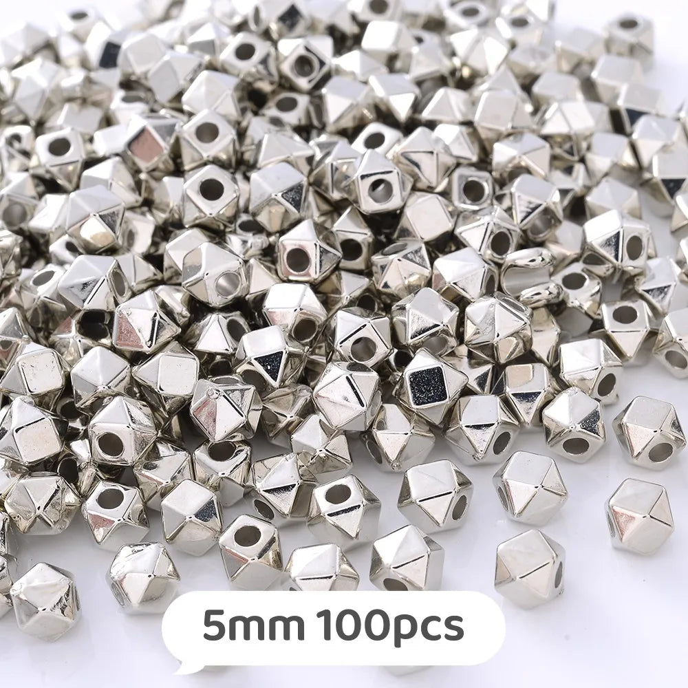 A pile of silver-toned geometric acrylic beads, approximately 5mm in size, for jewelry making.