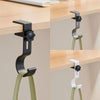 A black adjustable desk hook with dual clips is shown mounted on a wooden shelf.