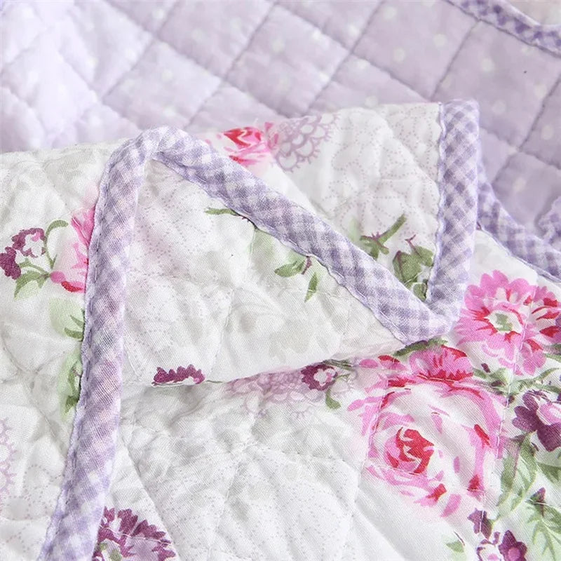 White quilted fabric with pink and purple floral print and plaid trim.