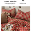 A red and green plaid duvet cover set with matching pillows and a stuffed bear toy.