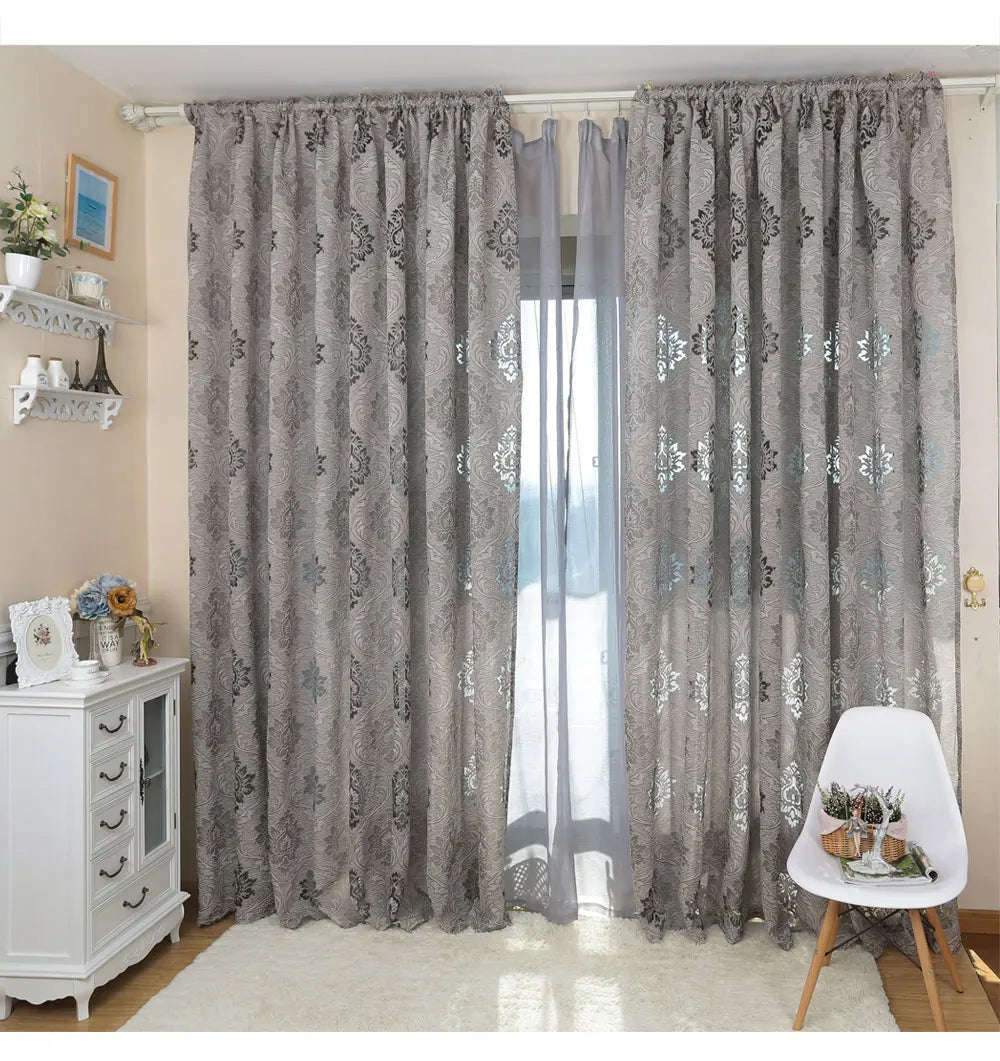 Gray sheer jacquard curtain panels hanging in a light-colored room.