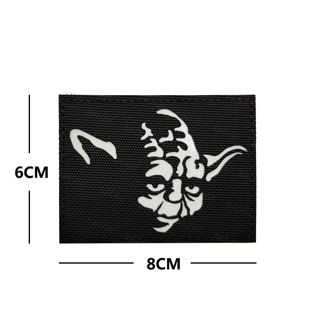 Black embroidered patch featuring a white stylized face design on a black fabric background