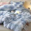 Light blue fluffy rabbit quilt comforter draped on a bed with blue and white pillows.
