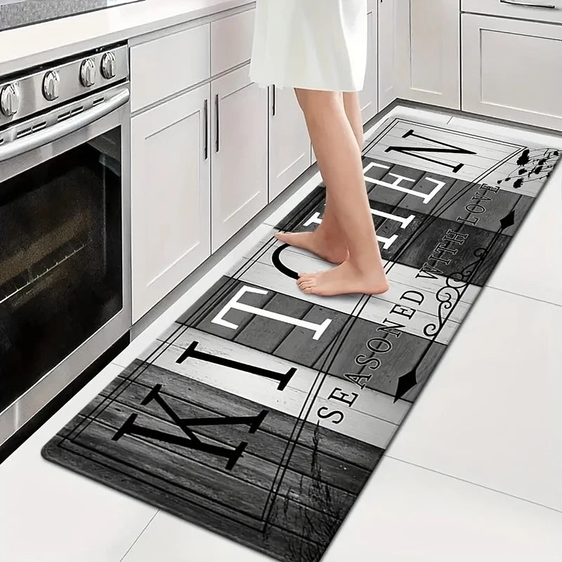 A black and white kitchen mat with text on it is placed on a white countertop next to a stainless steel oven.