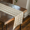 A beige and white checkered linen table runner draped over a dark wood farmhouse table.
