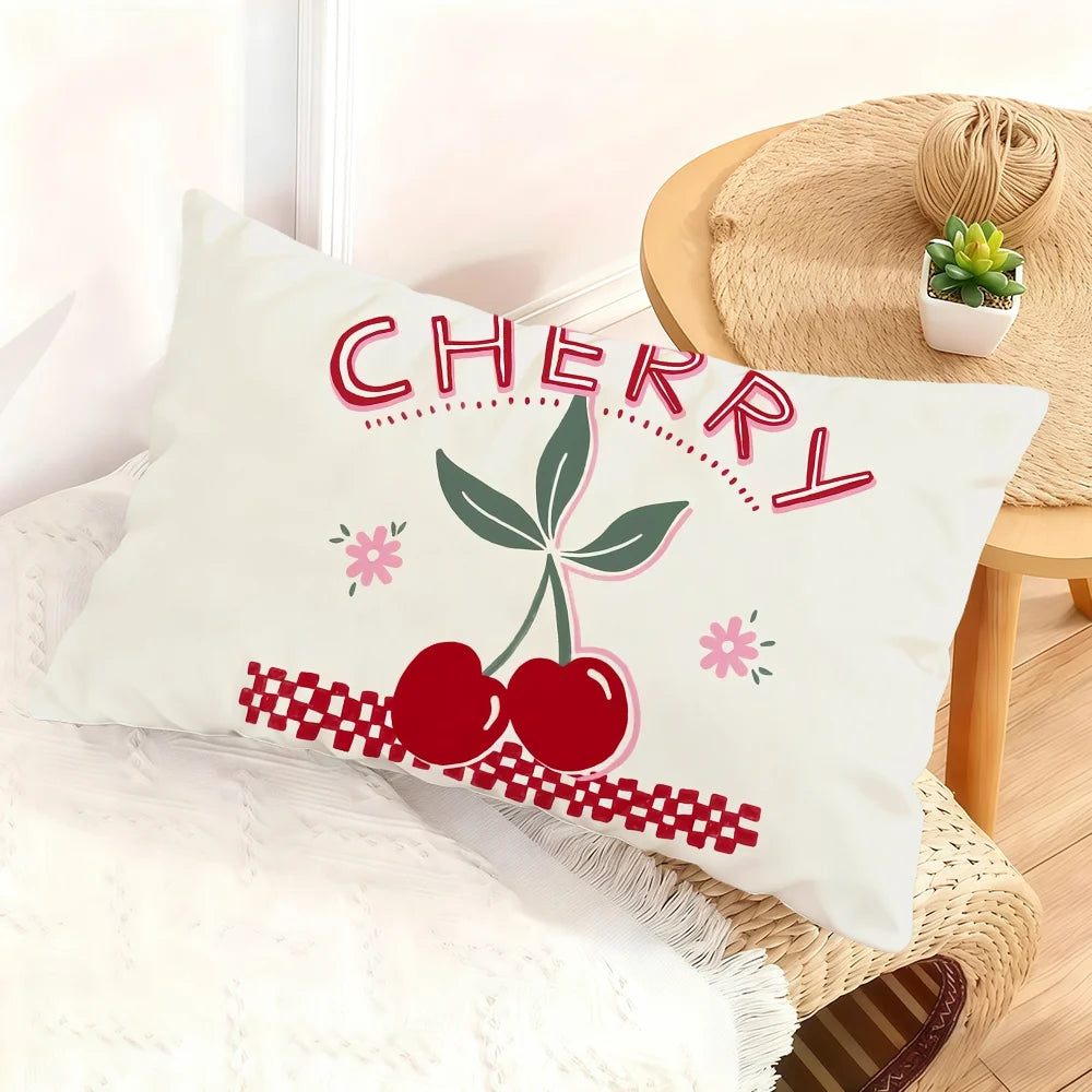 A white cushion cover featuring the word cherry in pink lettering and a red cherry design on a light background.