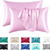 A set of pink satin pillowcases, including a main pillow and several folded fabric samples in various colors like green, beig