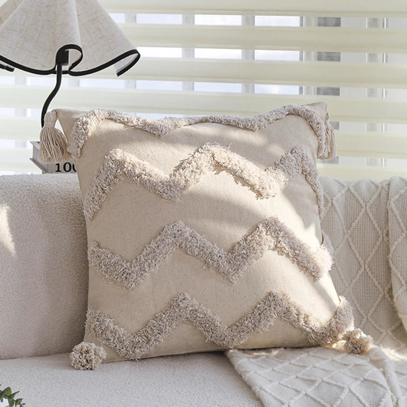 A beige cushion cover with a textured, zigzag embroidered pattern rests on a light-colored sofa.