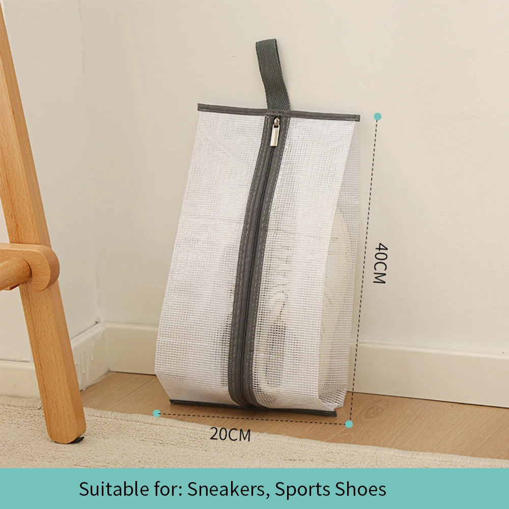 A white mesh portable boot storage bag with a gray zipper and carry handle, shown next to a wooden object.