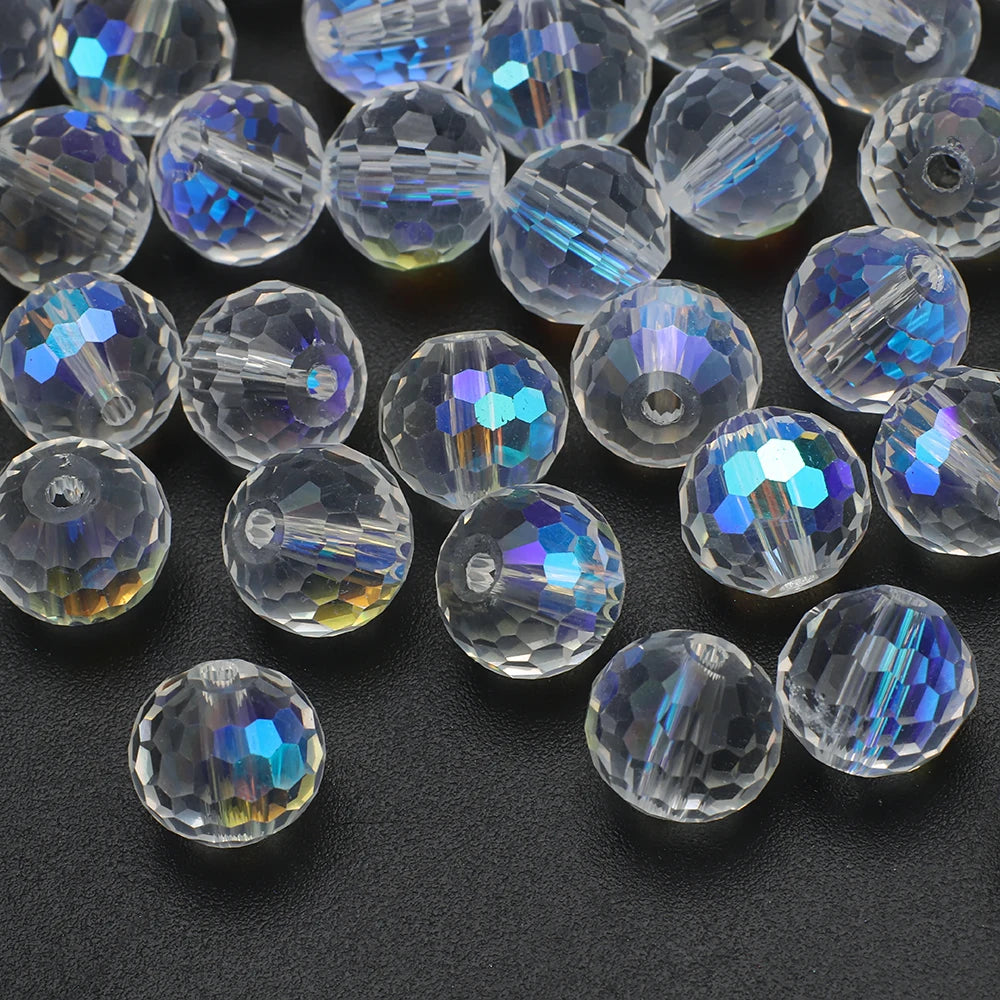 A collection of multi-size shiny AB crystal glass beads with faceted surfaces scattered on a dark surface.