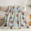 A light blue flannel throw blanket featuring repeating illustrations of Curious George characters.
