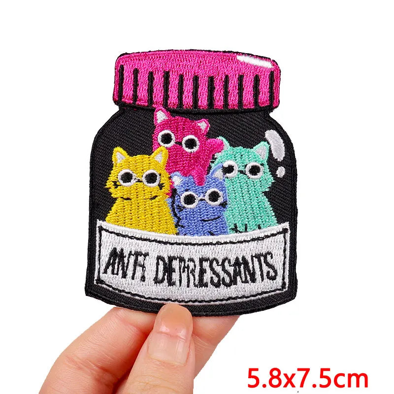 A set of embroidered iron-on patches featuring cartoon cats in various colors on a black fabric background.