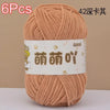 A skein of soft, bulky, light peach colored chenille yarn is shown in a ball.
