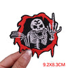 Black and white embroidered skull patch with outstretched fingers on a red background