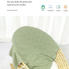 A light green knit baby blanket is draped over a wicker cradle, suggesting gentle care for an infant.