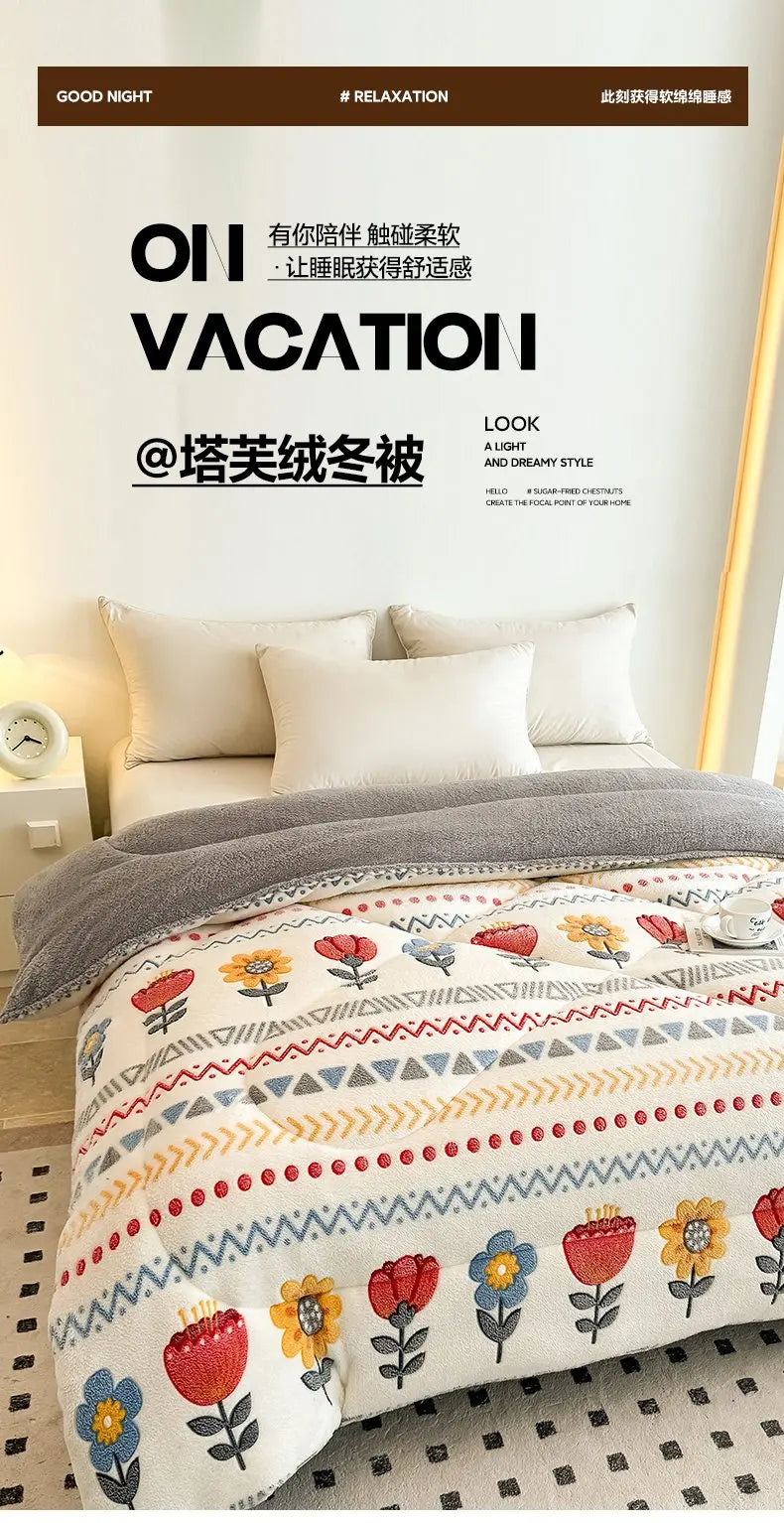 A cozy bed with a thick gray blanket featuring floral patterns and white pillows.