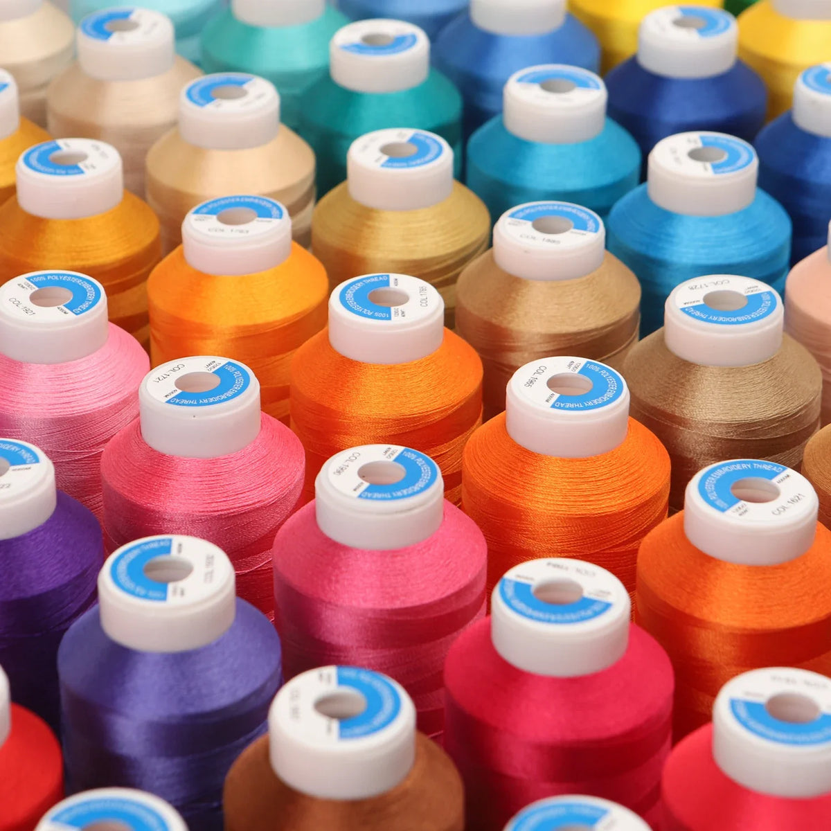 A collection of high tenacity machine embroidery thread in various shades including yellow, orange, pink, and blue.