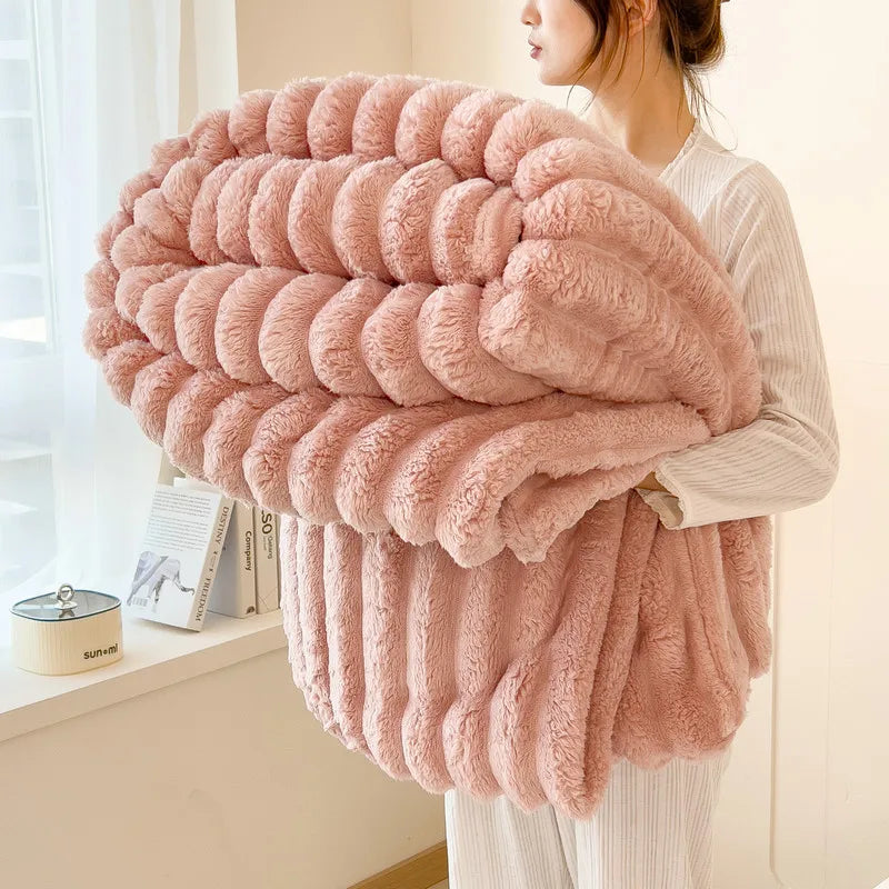 A woman holds a fluffy, pink, horizontally striped blanket made of soft faux fur.
