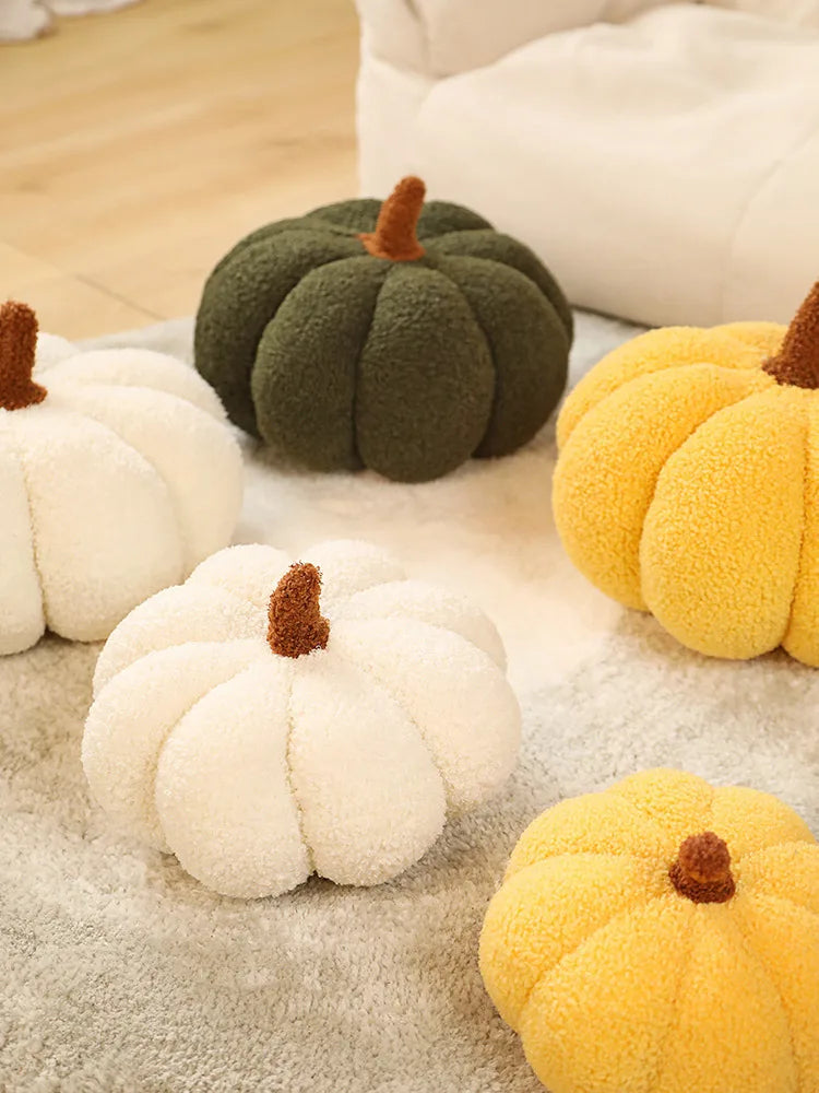 A collection of soft, fuzzy plush pumpkin throw pillows in cream, olive green, and yellow colors.