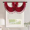 A deep red European style window curtain valance with tassels draped over a white window frame.