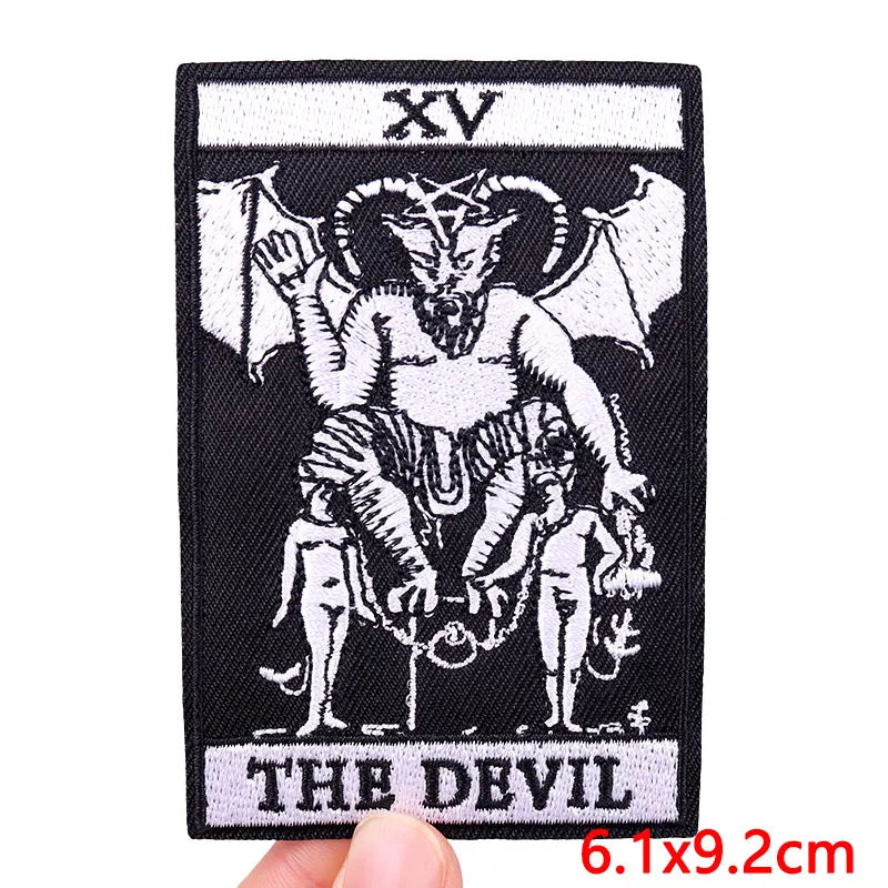 Black embroidery patch featuring a stylized devil skull design with horns and a small figure.
