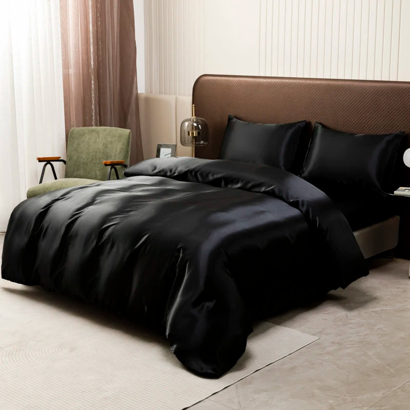 A black satin luxury bedding set is displayed on a bed with a brown headboard and light-colored curtains.