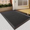 A black non-slip rubber mat is placed on a light gray floor in front of a white door frame.