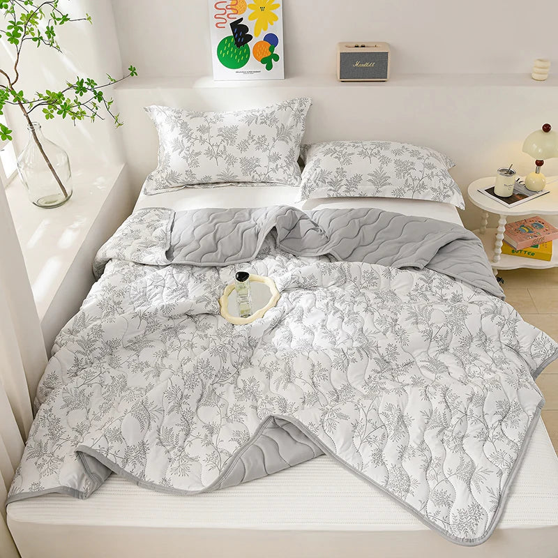 A white quilted lightweight cooling summer quilt set displayed on a bed with pillows and decorative items.
