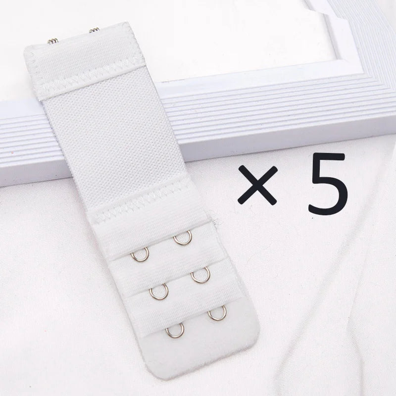 A white adjustable bra extender strap set with five small rings is displayed next to a picture frame.