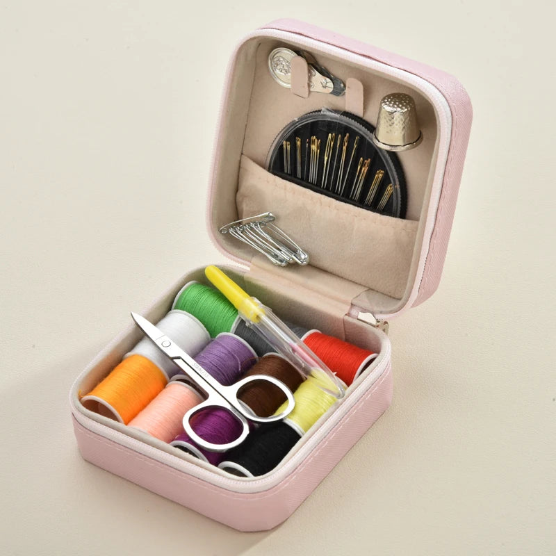 A pink leather sewing box containing a complete hand sewing kit with various needles and thread spools.