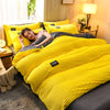 A bright yellow ribbed duvet cover set is displayed on a bed, with a woman relaxing under the covers.