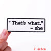 A white embroidered patch with the text That's what she sewn on a piece of fabric