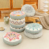 A collection of round bohemian tatami cushions in various floral and geometric patterns stacked on a light beige floor.