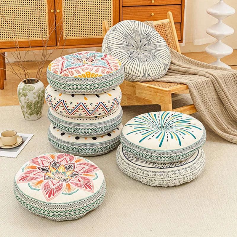 A collection of round bohemian tatami cushions in various floral and geometric patterns stacked on a light beige floor.