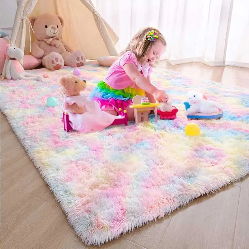 A young girl plays with stuffed animals and toys on a colorful rainbow plush area rug indoors.