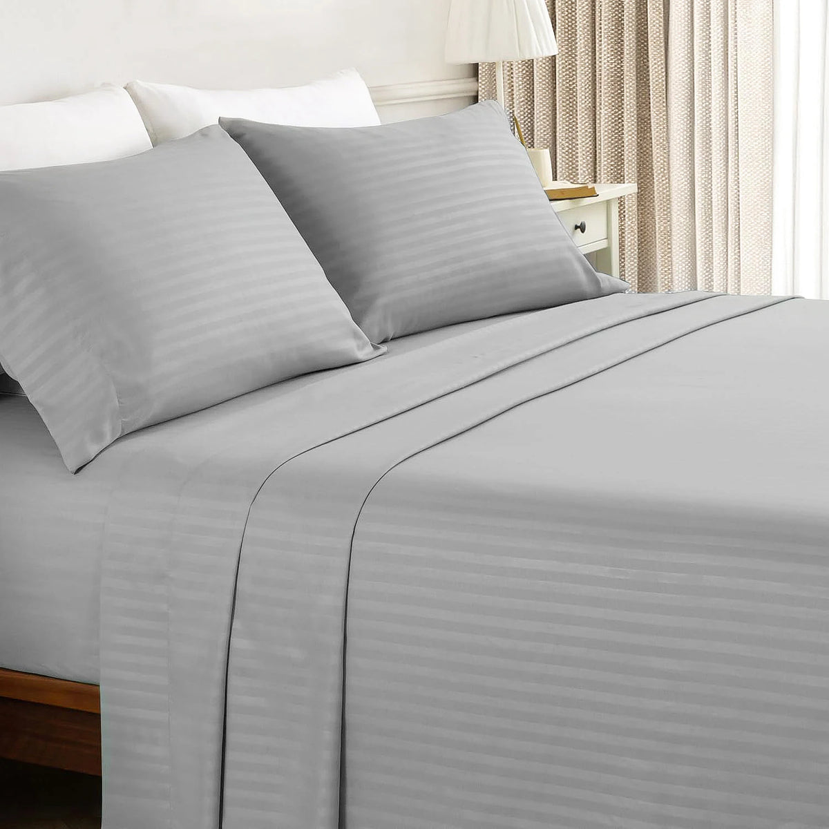 A gray luxury solid stripe bedding set featuring pillows and a fitted sheet on a bed.